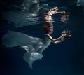 Girl in white dress posing under water with the boat