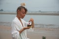 Girl in white dress sitting on the beach and eating cake with cherries