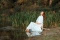 Girl white dress sitting dipping feet in the lake. Royalty Free Stock Photo