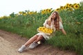 a girl in a white dress is sitting, resting and dreaming, on the edge of an unpaved dirt road. Royalty Free Stock Photo