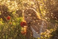 Girl in white dress smelling tulip in sunset among fluff, dandelions and cherry flowers Royalty Free Stock Photo