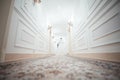 A girl in a white dress walking along a white corridor. Beautiful fashion girl walking along the corridor in a dress. Dress from