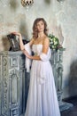 girl in a white evening dress standing by the fireplace