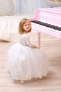 Girl in white gown at opened pink grand piano