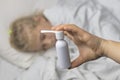 a girl with white hair lies in bed. mom using an inhaler makes an injection in the throat of a patient