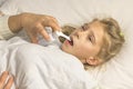 a girl with white hair lies in bed. mom using an inhaler makes an injection in the throat of a patient Royalty Free Stock Photo