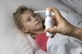 A girl with white hair lies in bed she is out of focus. mom using an inhaler makes an injection in the patient`s throat, she is i Royalty Free Stock Photo