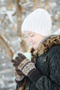 Girl in a white hat look in cup of tea. Winter, outdoors. Side v Royalty Free Stock Photo