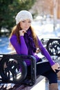 Girl in white hat sitting on a bench in winter Royalty Free Stock Photo