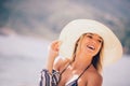 Girl in a white hat smiling at the summer waterfront