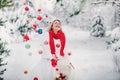A girl in a white jacket throws Christmas balls to decorate the Christmas tree.A girl throws Christmas decorations from a basket