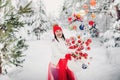 A girl in a white jacket throws Christmas balls to decorate the Christmas tree.A girl throws Christmas decorations from a basket