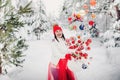 A girl in a white jacket throws Christmas balls to decorate the Christmas tree.A girl throws Christmas decorations from