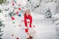 A girl in a white jacket throws Christmas balls to decorate the Christmas tree.A girl throws Christmas decorations from