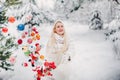 A girl in a white jacket throws Christmas balls to decorate the Christmas tree.A girl throws Christmas decorations from a basket