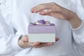 A girl in a white jumper holds a small box with a gift in one hand, the other hand touches it from above Royalty Free Stock Photo