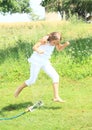 Girl in white jumping thru sprinkler Royalty Free Stock Photo