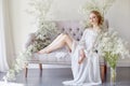 Girl white light dress and curly hair, portrait of woman with flowers at home near the window, purity and innocence. Curly blonde Royalty Free Stock Photo