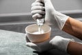 A girl in white protective gloves squeezes hair dye into an oxidizer. colorist at work close-up hair care hair mask hair