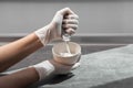 A girl in white protective gloves squeezes hair dye into an oxidizer. colorist at work close-up hair care hair mask