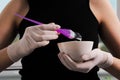 Girl in white rubber protective gloves holding a brush in her hands and stirring hair dye close-up colorist hair care at home Royalty Free Stock Photo