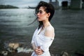 A girl in a white shirt stands on the river Bank during a strong wind Royalty Free Stock Photo