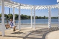 girl in a white shirt and a straw hat is swinging on a swing in the park under a white canopy that protects from the sun Royalty Free Stock Photo