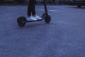 Girl in white sneakers driving an electric scooter in dusk Royalty Free Stock Photo