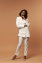 Girl in white suit posing on beige background Royalty Free Stock Photo