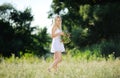 Girl in a white sundress and with a wreath of flowers in hand on Royalty Free Stock Photo