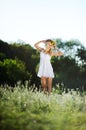 girl in a white sundress and a wreath of flowers on her head against a background of trees. Royalty Free Stock Photo