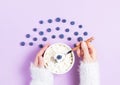 Girl in a white sweater holds a plate with grained cottage cheese and blueberries in a spoon on a pink background Royalty Free Stock Photo