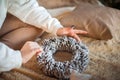 A girl in a white sweater makes a wreath of fir cones. Woman in a bedroom interior in Rustic style for Christmas and New Year. DIY