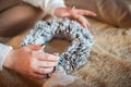 A girl in a white sweater makes a wreath of fir cones. Woman in a bedroom interior in Rustic style for Christmas and New Year. DIY