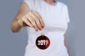 Girl in white t-shirt holding Christmas toy red ball with inscription 2017.