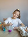 A girl in a white T-shirt paints Easter colored eggs with paints and a brush close-up.The child holds the painted eggs.. Spring. Royalty Free Stock Photo