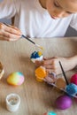 he child holds the painted eggs. A girl in a white T-shirt paints Easter colored eggs with paints and a brush close-up. Royalty Free Stock Photo