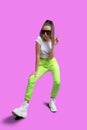 Girl in a white T-shirt and yellow neon sweatpants on a pink background