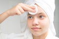 Girl with a white towel on her head in the bathroom, cleans her face with a cotton swab, close-up Royalty Free Stock Photo