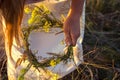 A girl in white traditional Slavic dress wreathes a wreath of fresh wildflowers at sunset. Russian traditions