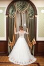 Girl in a white wedding dress by the window. Against the background of the window is a beautiful woman in a white wedding dress Royalty Free Stock Photo