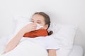 A girl who is sick, lies in a white bed and wipes her nose with a paper handkerchief Royalty Free Stock Photo