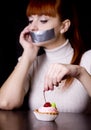 The girl, whose mouth sealed with tape sad looking at cakes Royalty Free Stock Photo