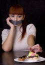 The girl, whose mouth sealed with tape sad looking at plate with Royalty Free Stock Photo