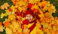 A girl with a wide smile lies on a carpet of red and yellow leaves in an autumn park. Royalty Free Stock Photo