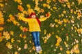 A girl with a wide smile is lies on a carpet of red and yellow leaves in an autumn park. Royalty Free Stock Photo