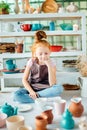 Girl wih many cups made from clay sitting in pottery studio Royalty Free Stock Photo