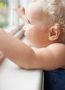 Girl, window and baby with smile standing against glass or wall in family home learning to walk. Happy, female toddler Royalty Free Stock Photo