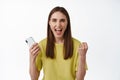 Girl winning on mobile phone. Happy woman celebrating success, holding smartphone and shouting with joy, triumphing Royalty Free Stock Photo