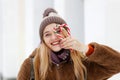 Girl in winter clothes and a hat holds two caramel candy canes and making heart shape. Royalty Free Stock Photo